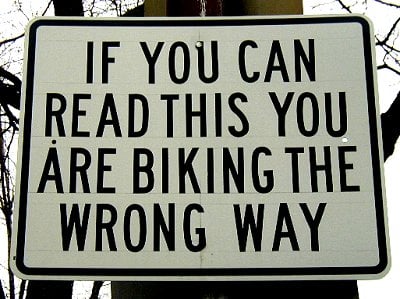 Sign on a street in Cambridge, MA reading: IF YOU CAN READ THIS YOU ARE BIKING THE WRONG WAY.
