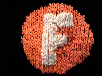 The F symbol from the F train proper, excellently and beautifully hand-knitted into a black scarf, and presented to me as a Christmas gift by my outstanding and wonderful girlfriend.