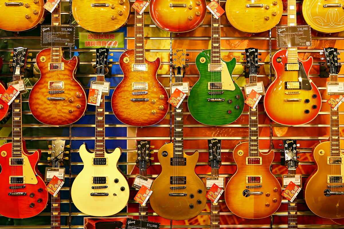 Photograph of three rows of guitars on the wall of a shop.
