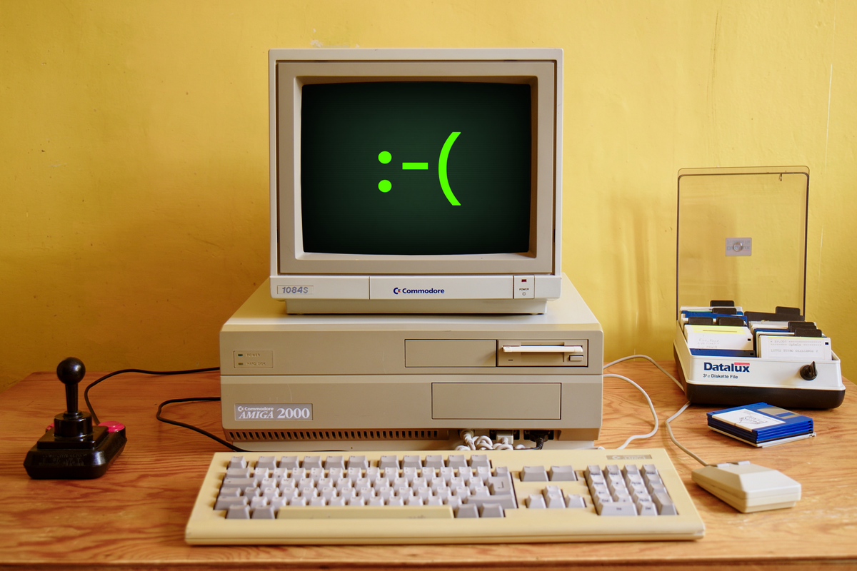 Image of an older computer with a green frowny face on the screen.