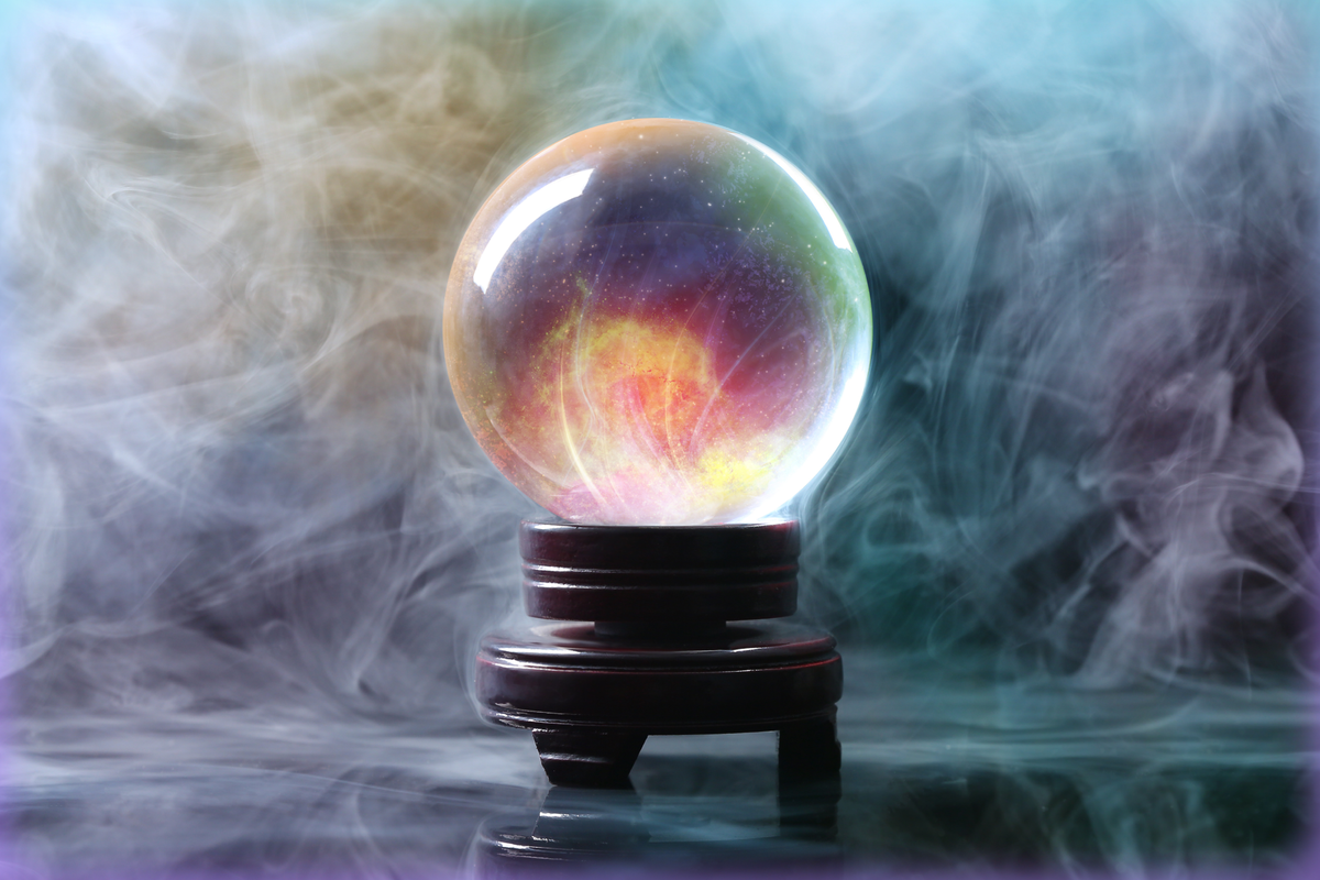 Photograph of a crystal ball sitting amid swirling multicolored smoke.