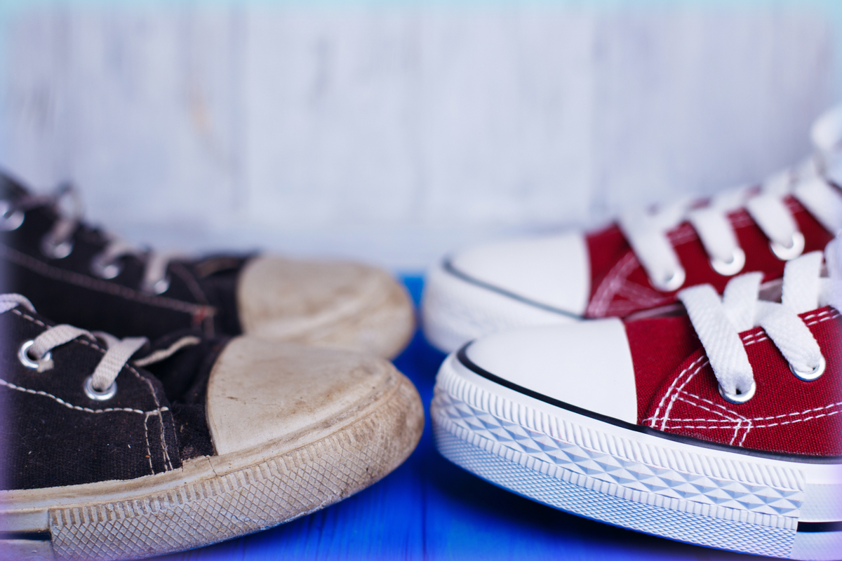 Photograph of two pairs of sneakers, one old and dirty and one new.