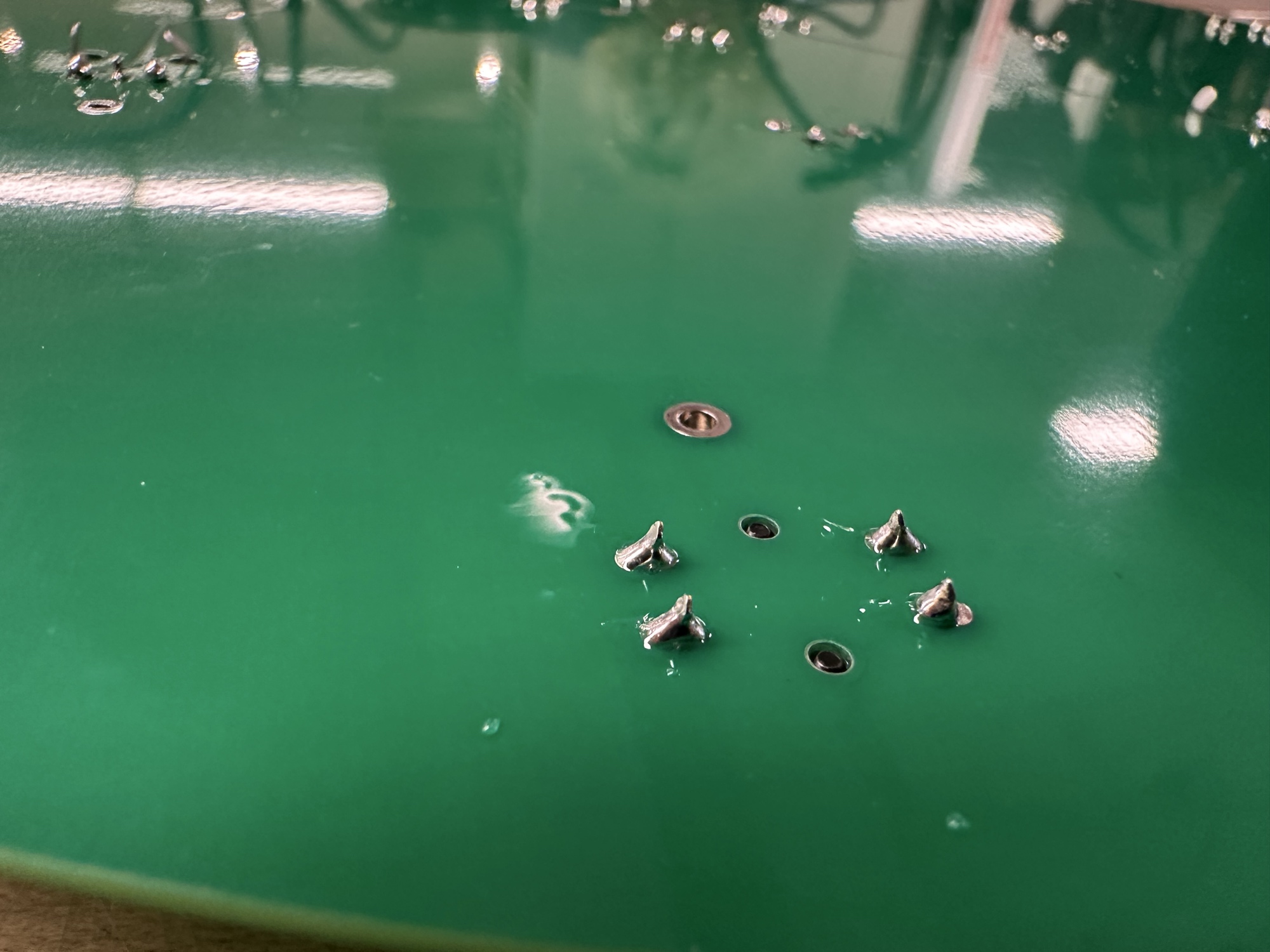 Some okay soldering work. Little metal peaks coming out of a green PCB.