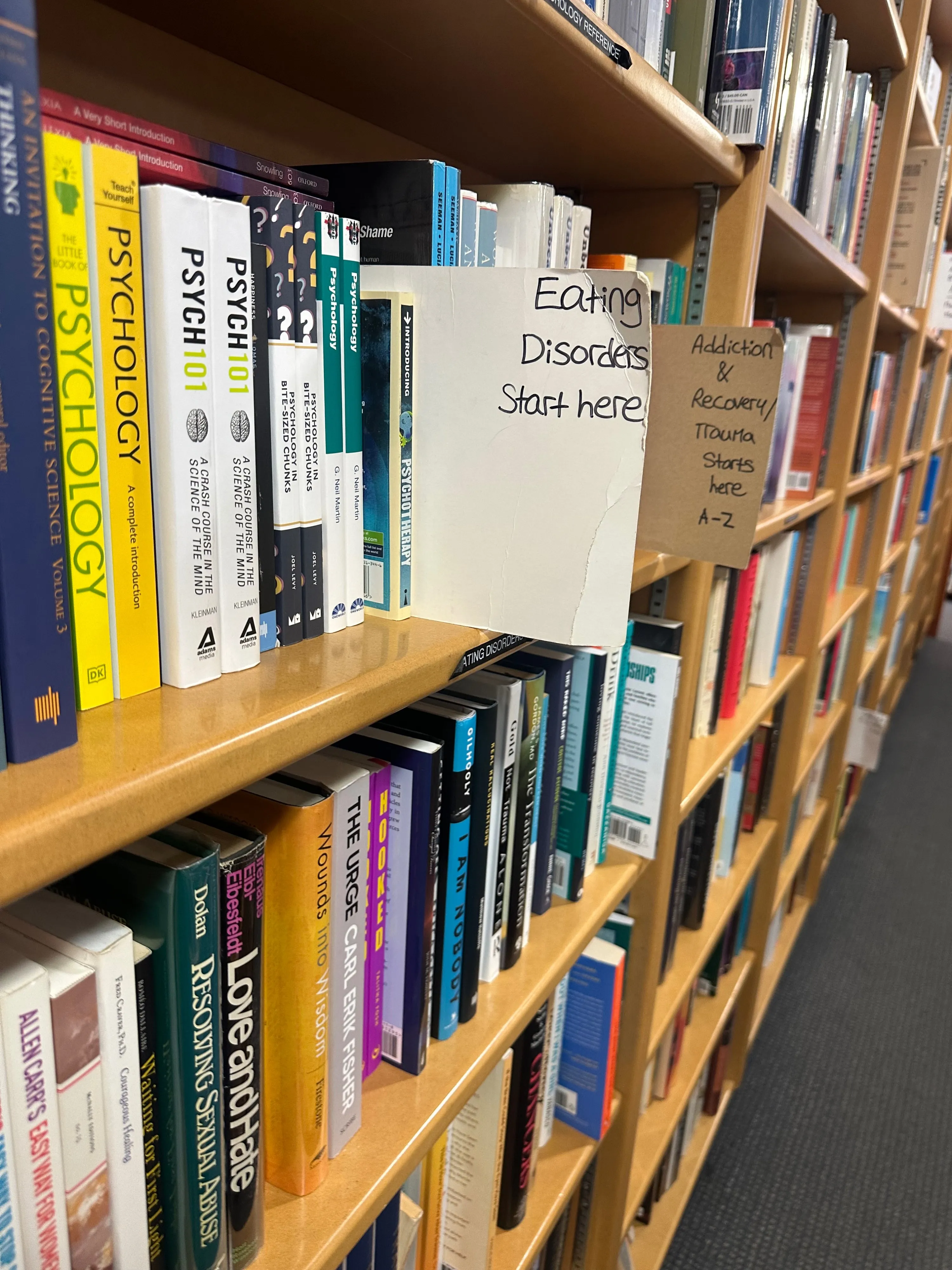 A bookstore bookshelf with a bunch of psychology books; a sign says “Eating Disorders Start here.”